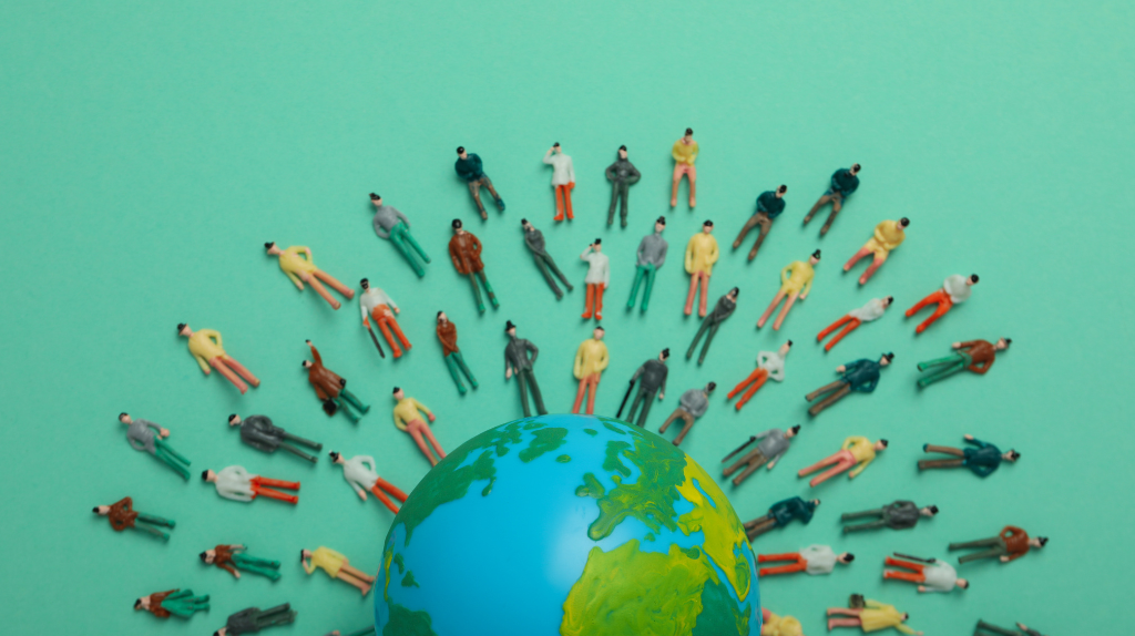 An image of the earth with many toy people standing on top of it